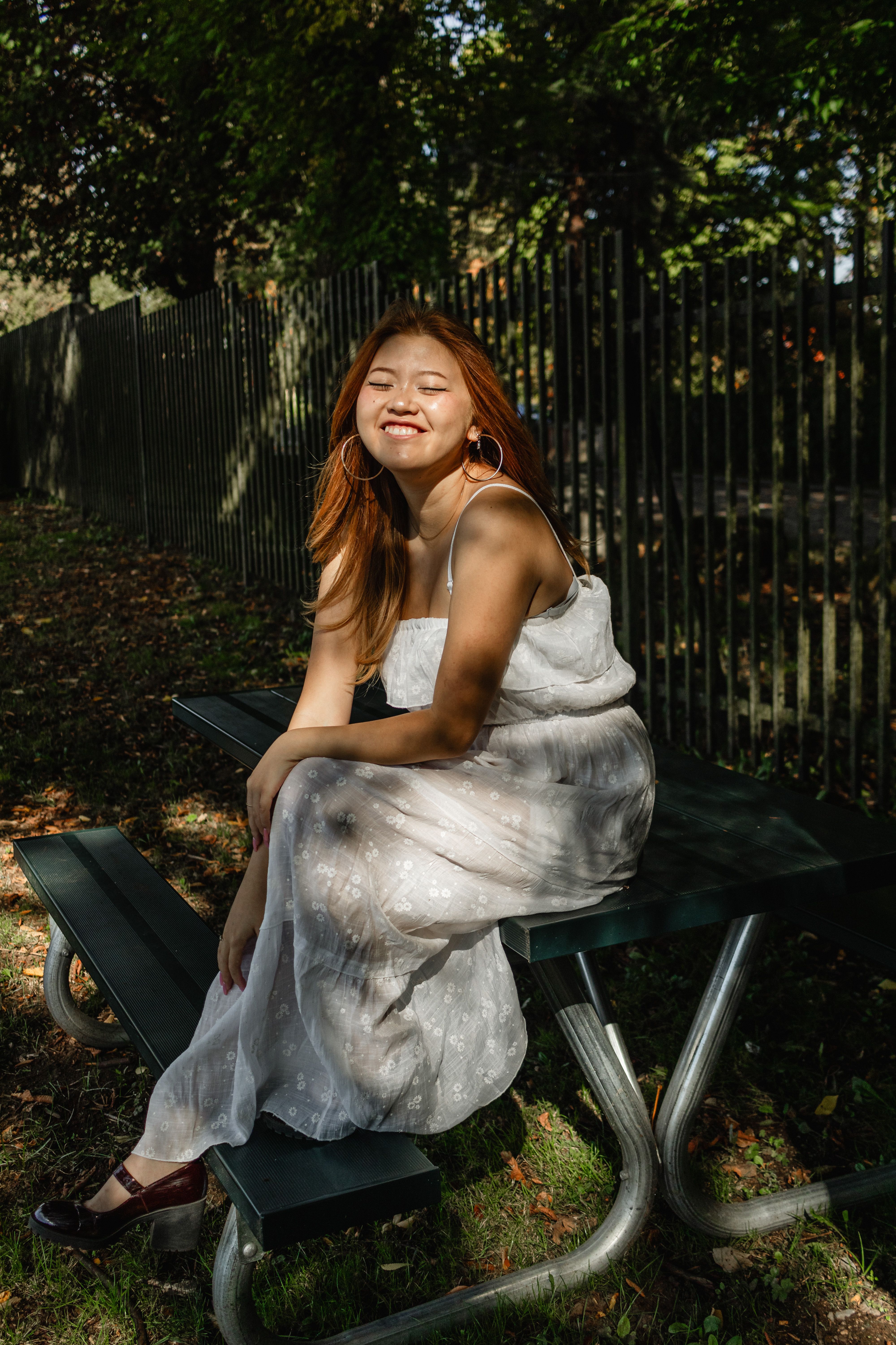 Smiling Woman in White Dress Sitting on Table · Free Stock Photo