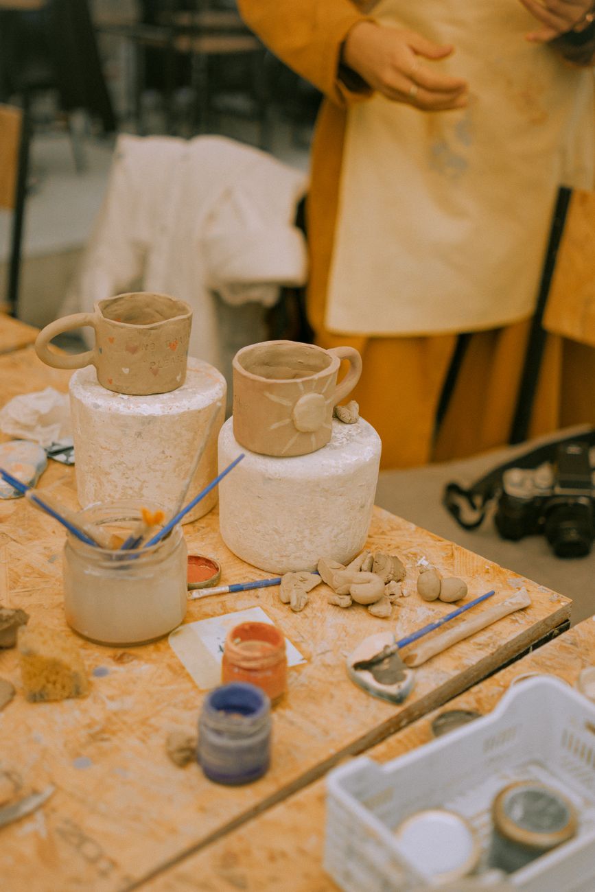 Artisan pottery workspace with handmade cups and clay jars in progress on a crafting table.