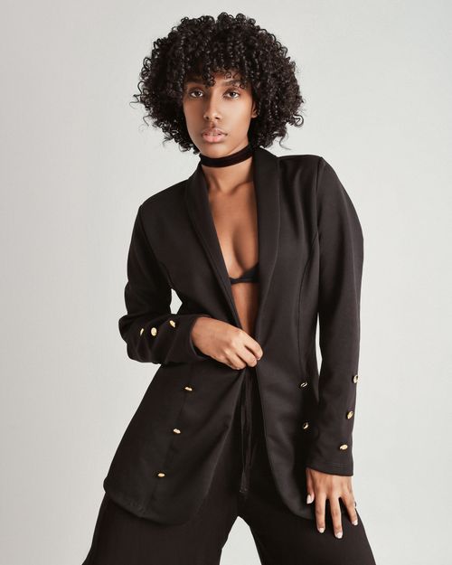 Free A striking black woman in a black suit showcasing elegance and modern fashion on a plain background. Stock Photo
