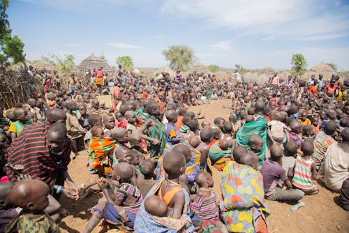 A Crowd Sitting Outside in an African Village 