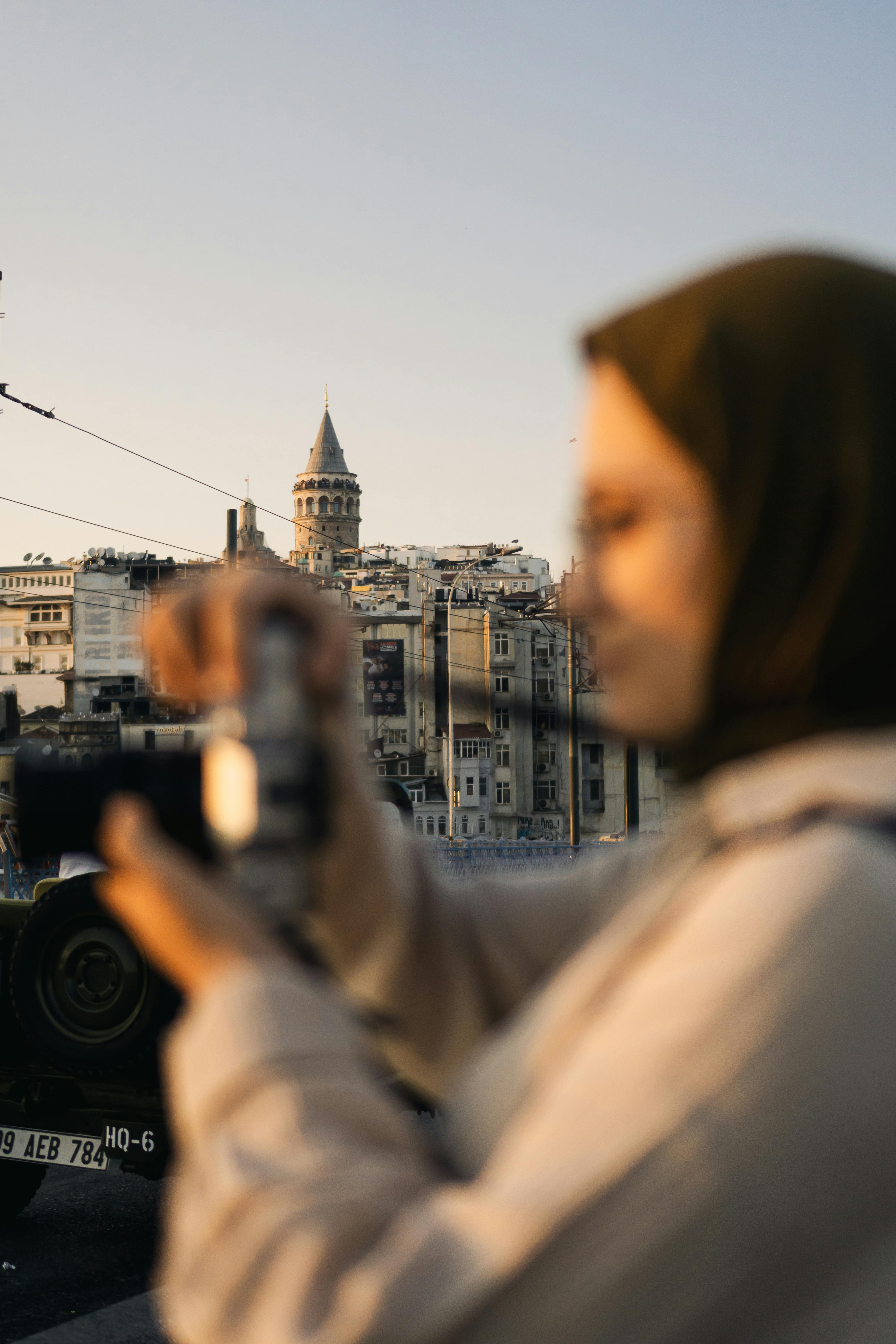 Free Woman with hijab taking photo of iconic Galata Tower in Istanbul at sunset. Stock Photo