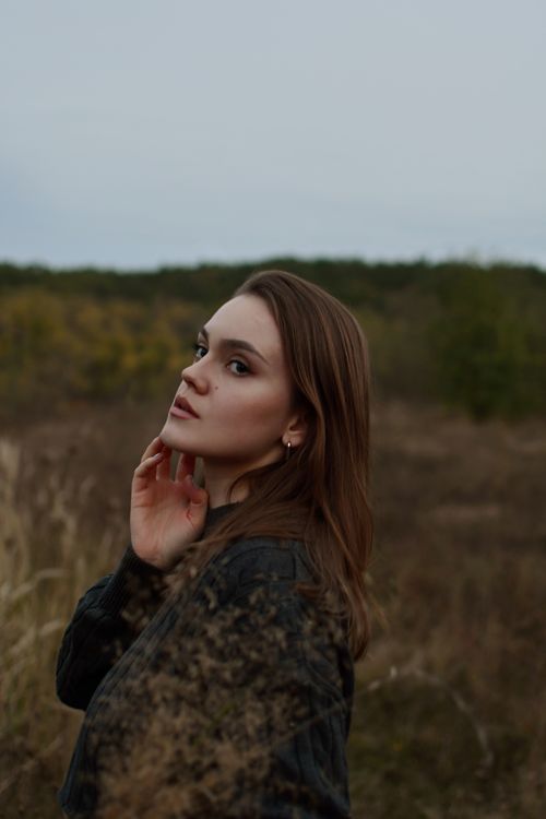 Free A thoughtful woman stands in a rural fall landscape, evoking serenity and introspection. Stock Photo