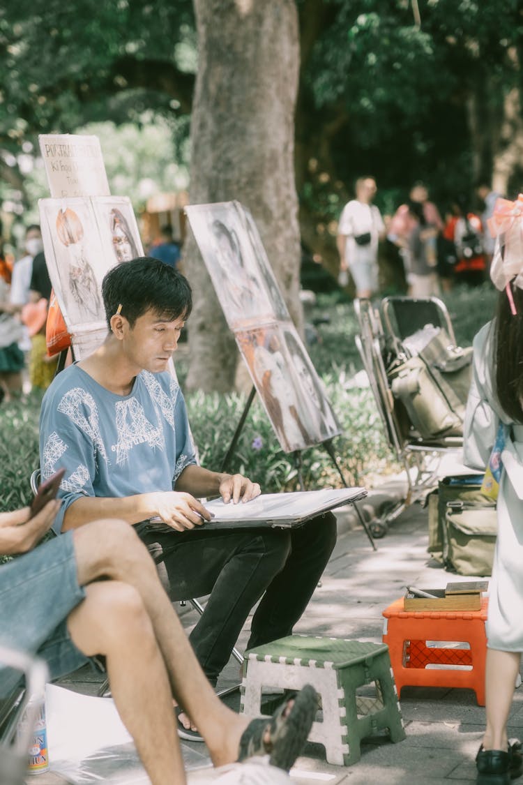 Man Sitting At Park And Drawing