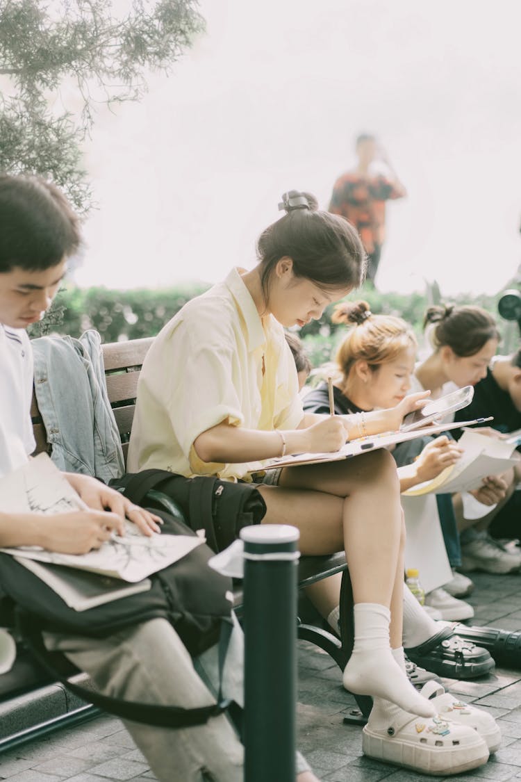 Students Sitting On Bench And Studying