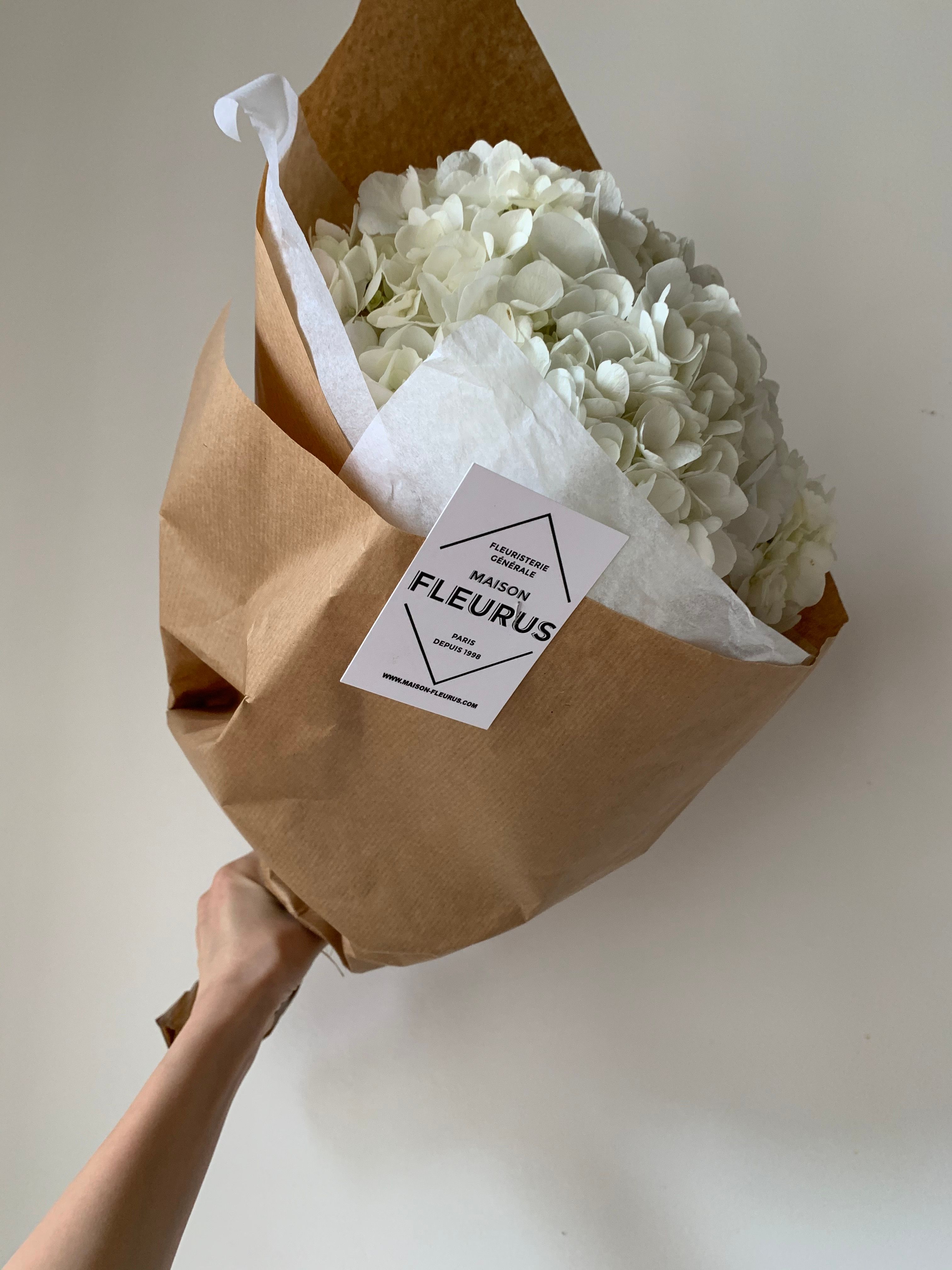 A hand holding a bouquet of white sympathy flowers