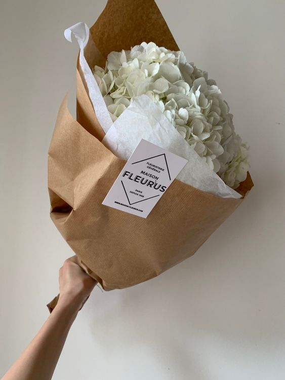 A hand holding a bouquet of white sympathy flowers