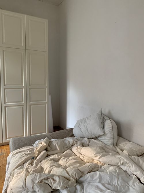 Free A minimalistic bedroom featuring white bedding and a wardrobe, offering a serene indoor setting. Stock Photo