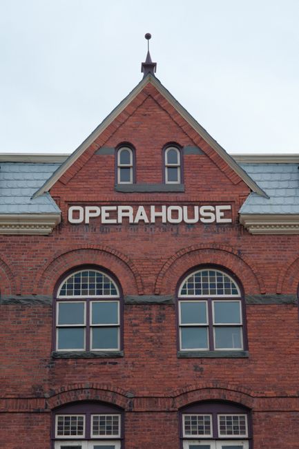Close-up of a vintage opera house facade with red brick and arched windows.