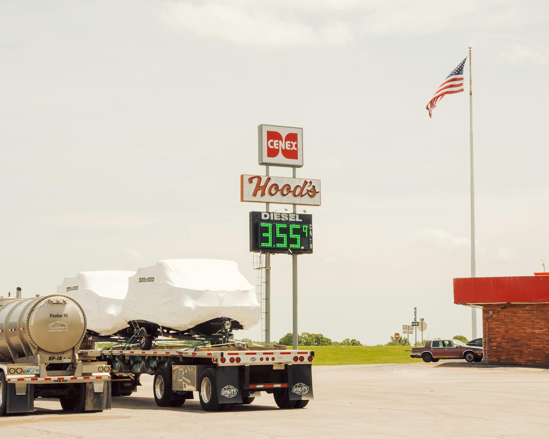 A rural gas station showing diesel price, featuring trucks and American flag.