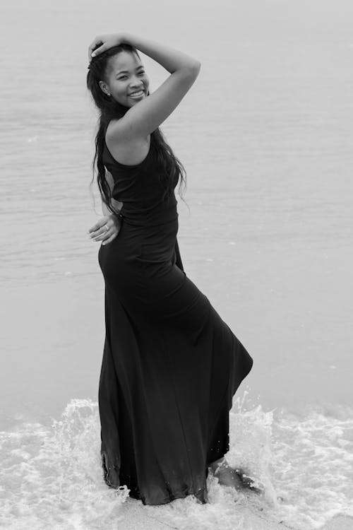 Smiling Model in Black Dress on Sea Shore