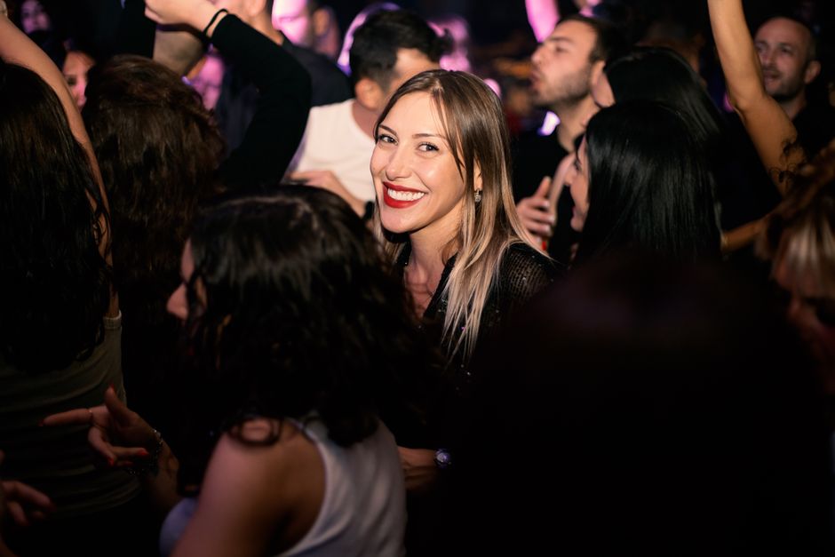 Woman enjoying a lively nightclub party with a smiling crowd.