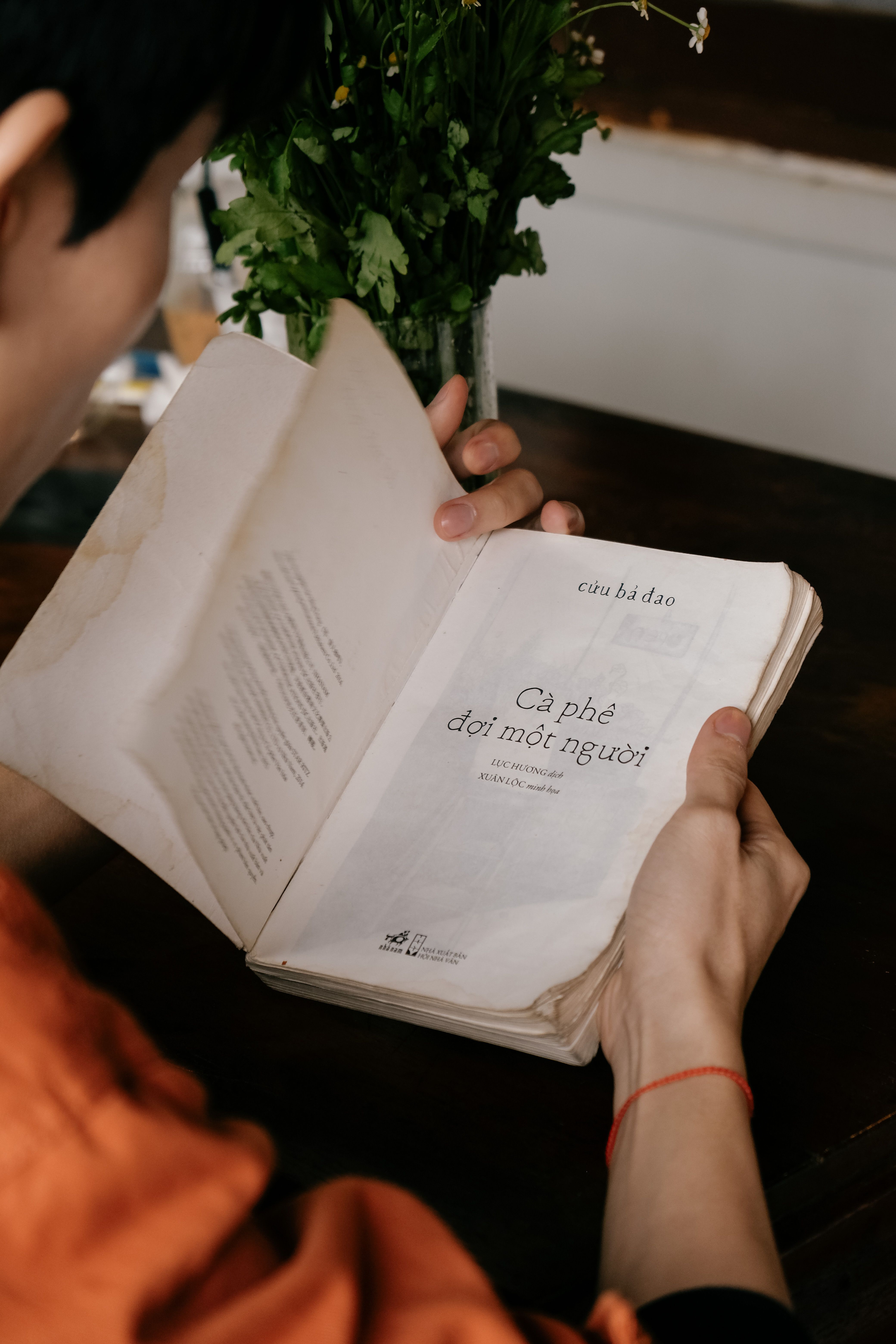 Close-up of a person reading a book at a cafe in Dalat, Vietnam.
