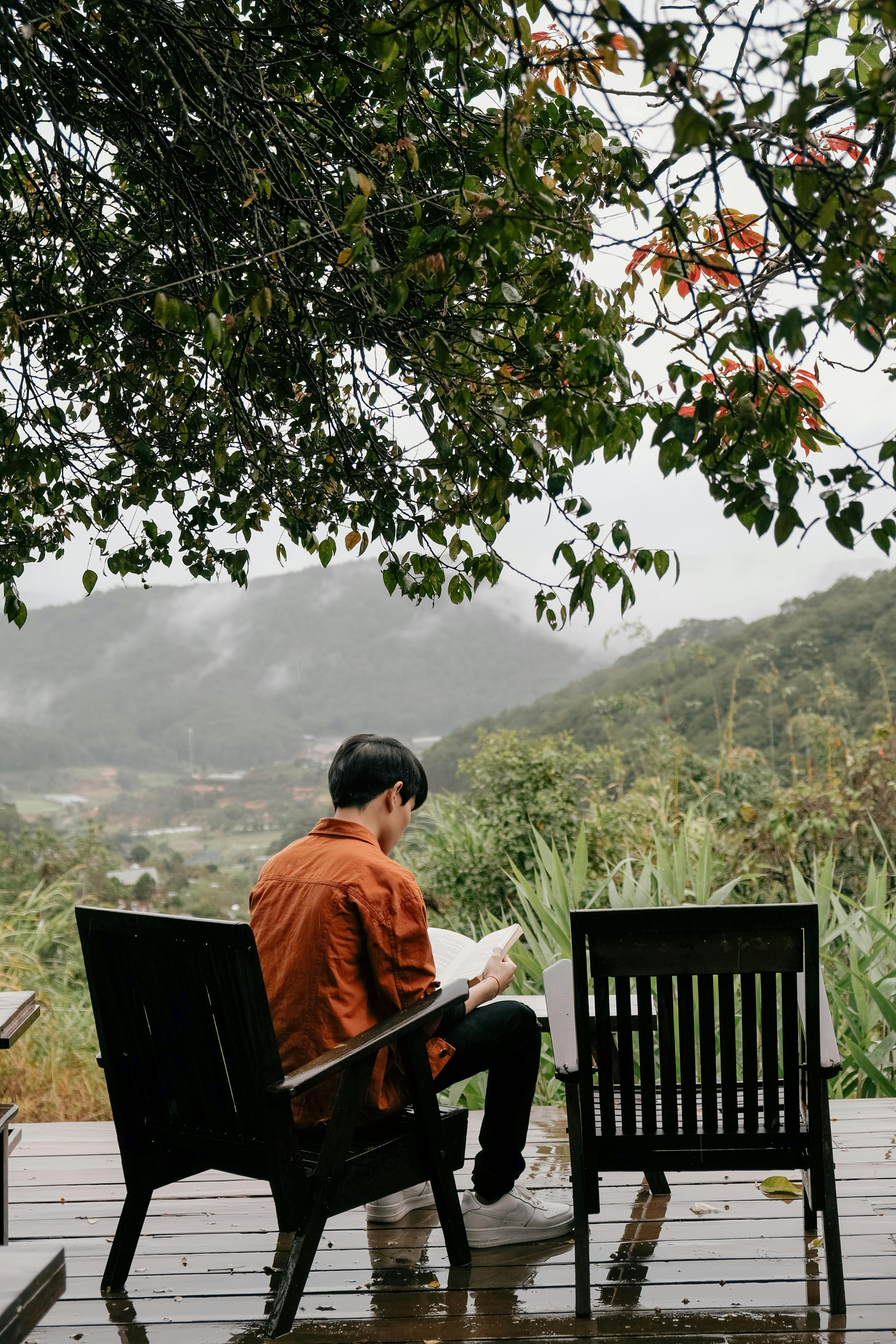 Adult male enjoys peaceful reading outdoors in Dalat, Vietnam's lush mountains.