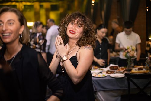 Free Cheerful woman with curly hair enjoying a lively indoor party with friends. Stock Photo