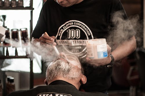 A barber brushing powder on a man's beard