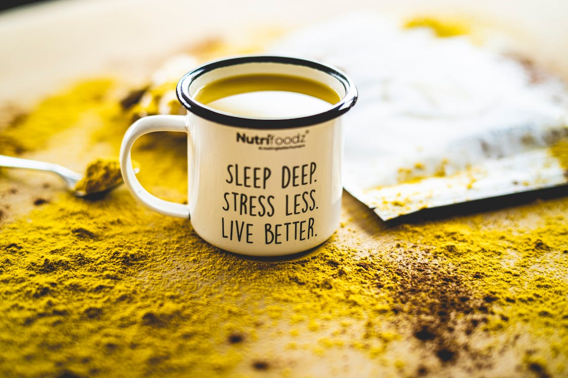 Free A motivational mug sits on vibrant turmeric powder, promoting relaxation and wellness. Stock Photo