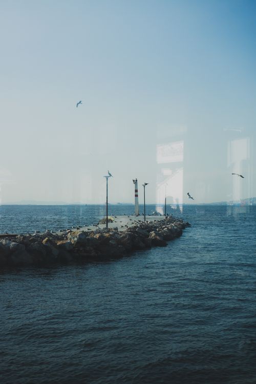 Free Serene coastal scene in Izmir featuring a pier, seabirds, and the open sea under a clear sky. Stock Photo
