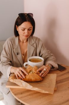Woman enjoying flatbread and soup at a cozy café table indoors.