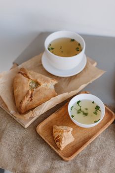 Appetizing soup served with flaky pastry on a wooden tray, shot from above for a rustic meal presentation.