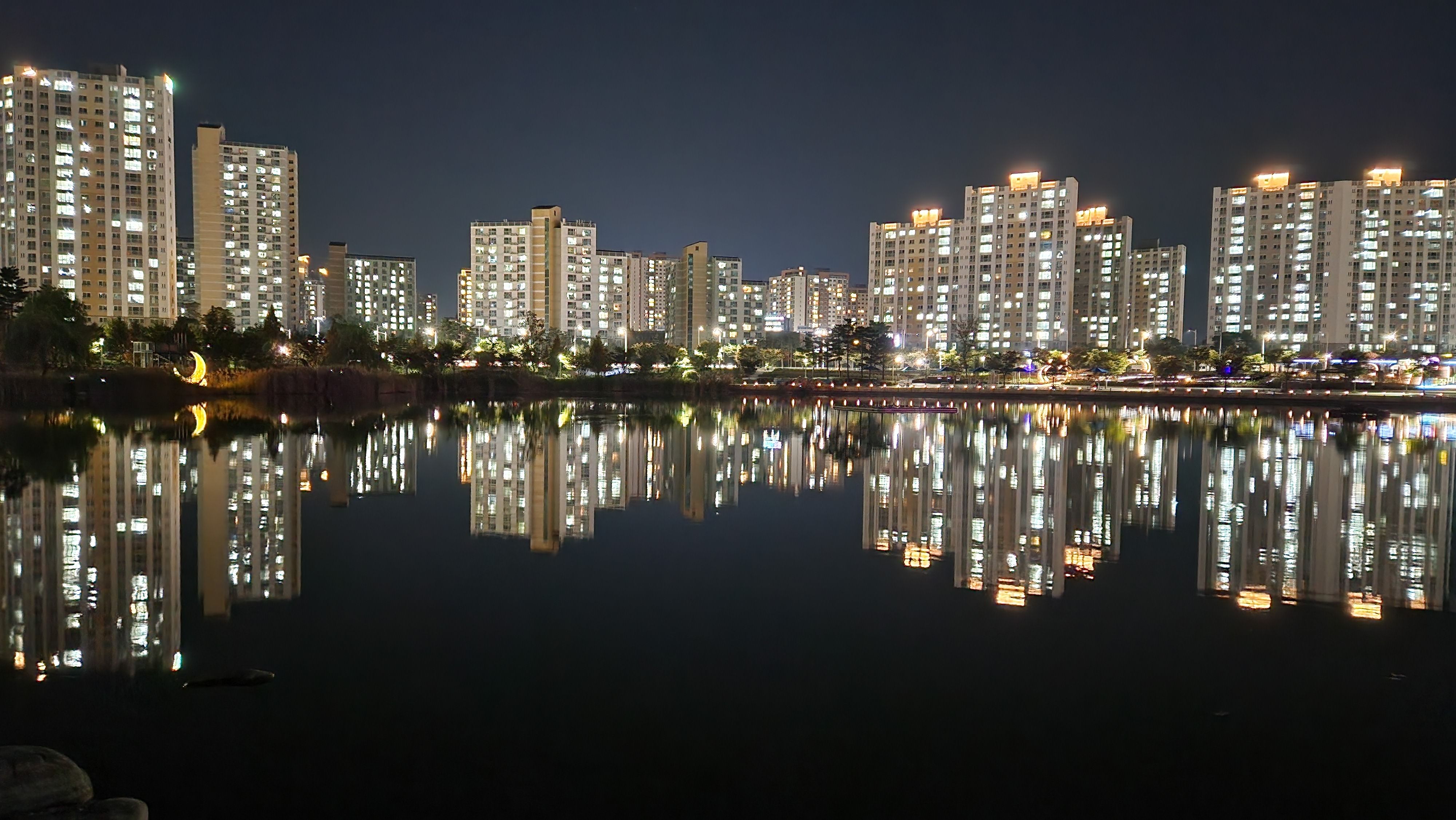 Stunning night view of illuminated buildings reflecting on a calm lake in Gimpo-si, South Korea.
