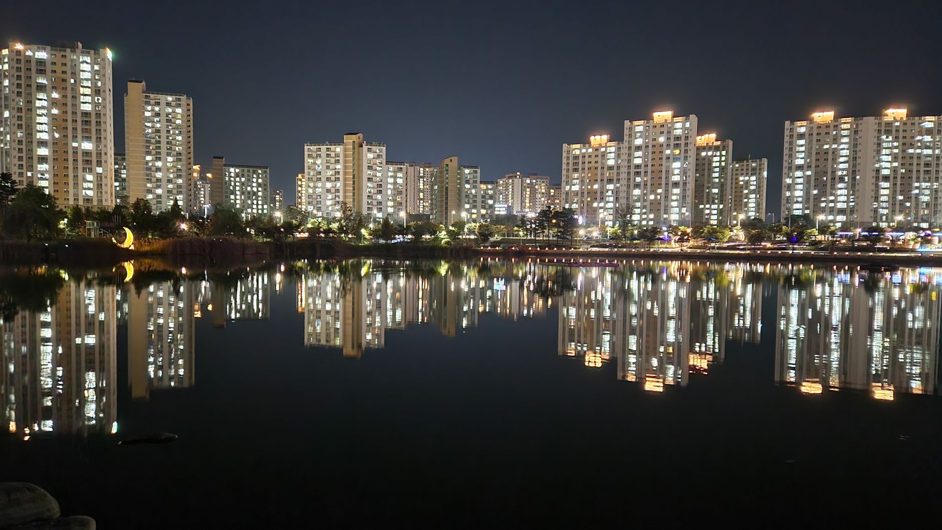 Stunning night view of illuminated buildings reflecting on a calm lake in Gimpo-si, South Korea.