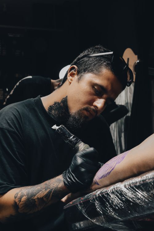 Free A skilled tattoo artist focused on creating a detailed tattoo on a client's arm in a studio. Stock Photo