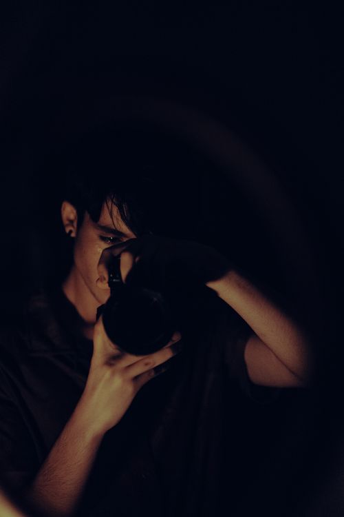 Free Mysterious portrait of a photographer capturing moments in dark, low light setting. Stock Photo