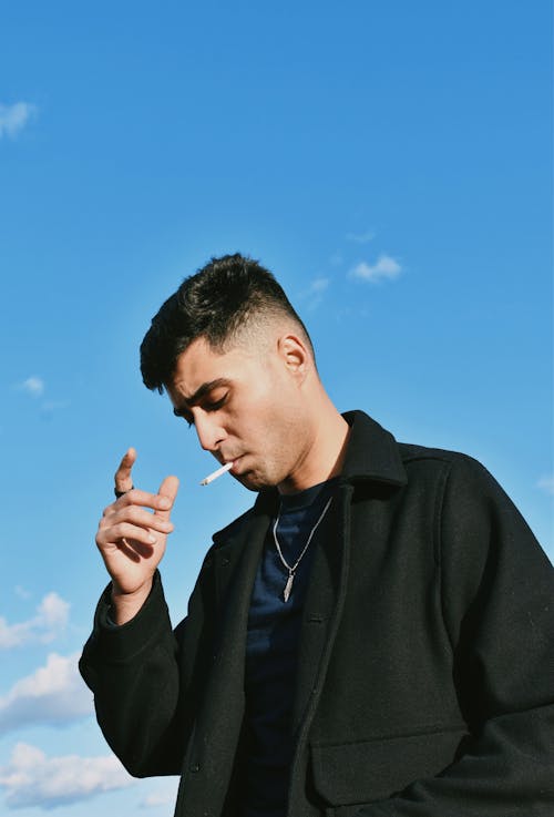 Young Man Smoking against Blue Sky