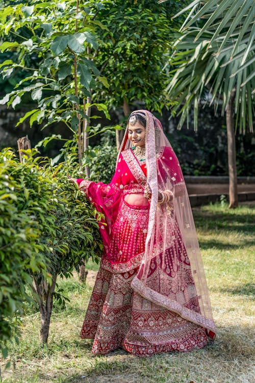 Woman in Red Traditional Bridal Saree Standing in a Park