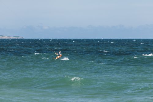 Free A kitesurfer enjoying an adventurous ride on the deep blue ocean waves during a sunny day. Stock Photo