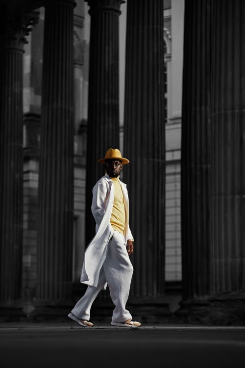 Free Fashionable man in stylish attire walking by historic columns in Potsdam, Germany, capturing urban elegance. Stock Photo
