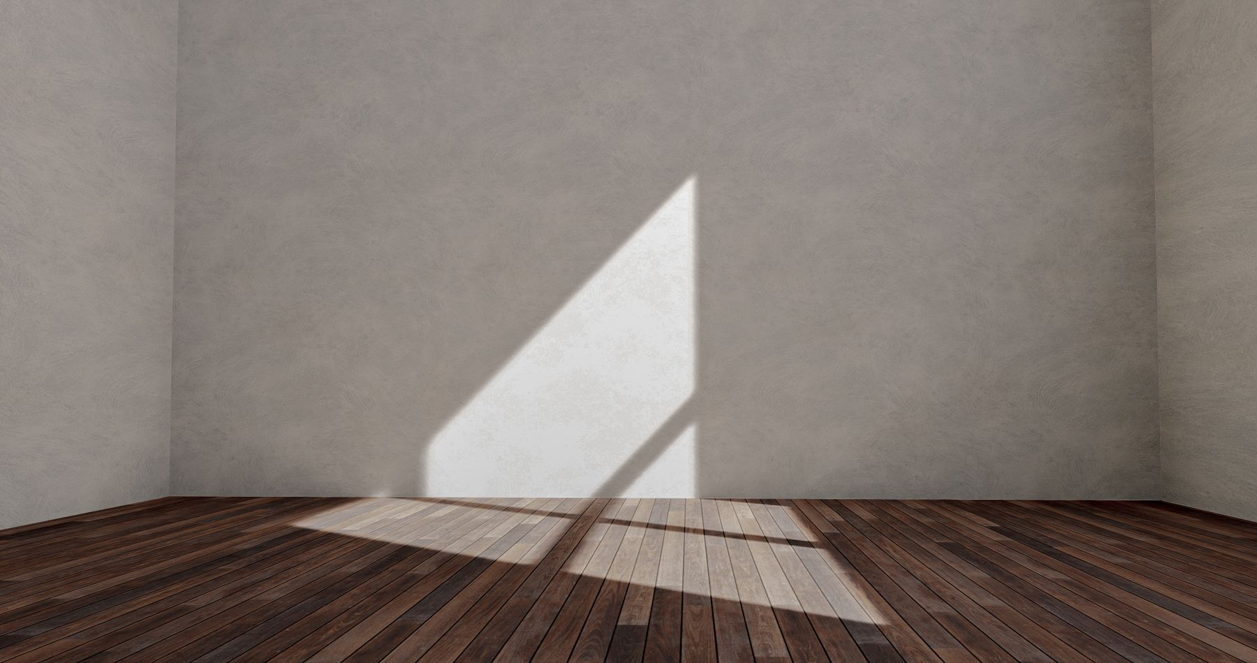 Sunlight from a window falling across the wood floor of an empty room