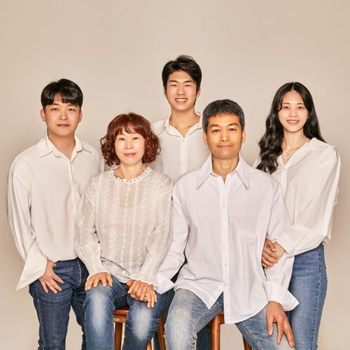 Free A cheerful family portrait featuring parents and children in a studio setting, smiling warmly. Stock Photo