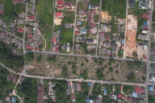 A bird's eye view of a suburban area showing houses, roads, and green spaces.