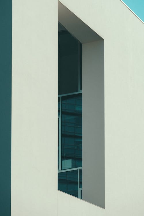 Низкоугольная фотография белого бетонного здания под голубым небом