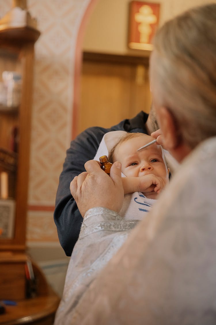 Priest Christening Newborn Baby In Church