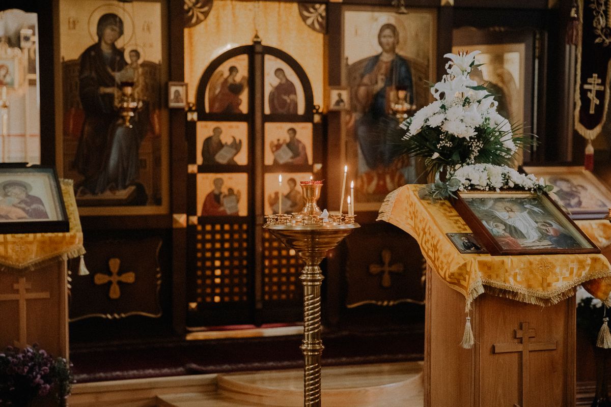 Altar ortodox împodobit cu icoane, lumânări aprinse și cărți de slujbă — interior de biserică în timpul slujbei