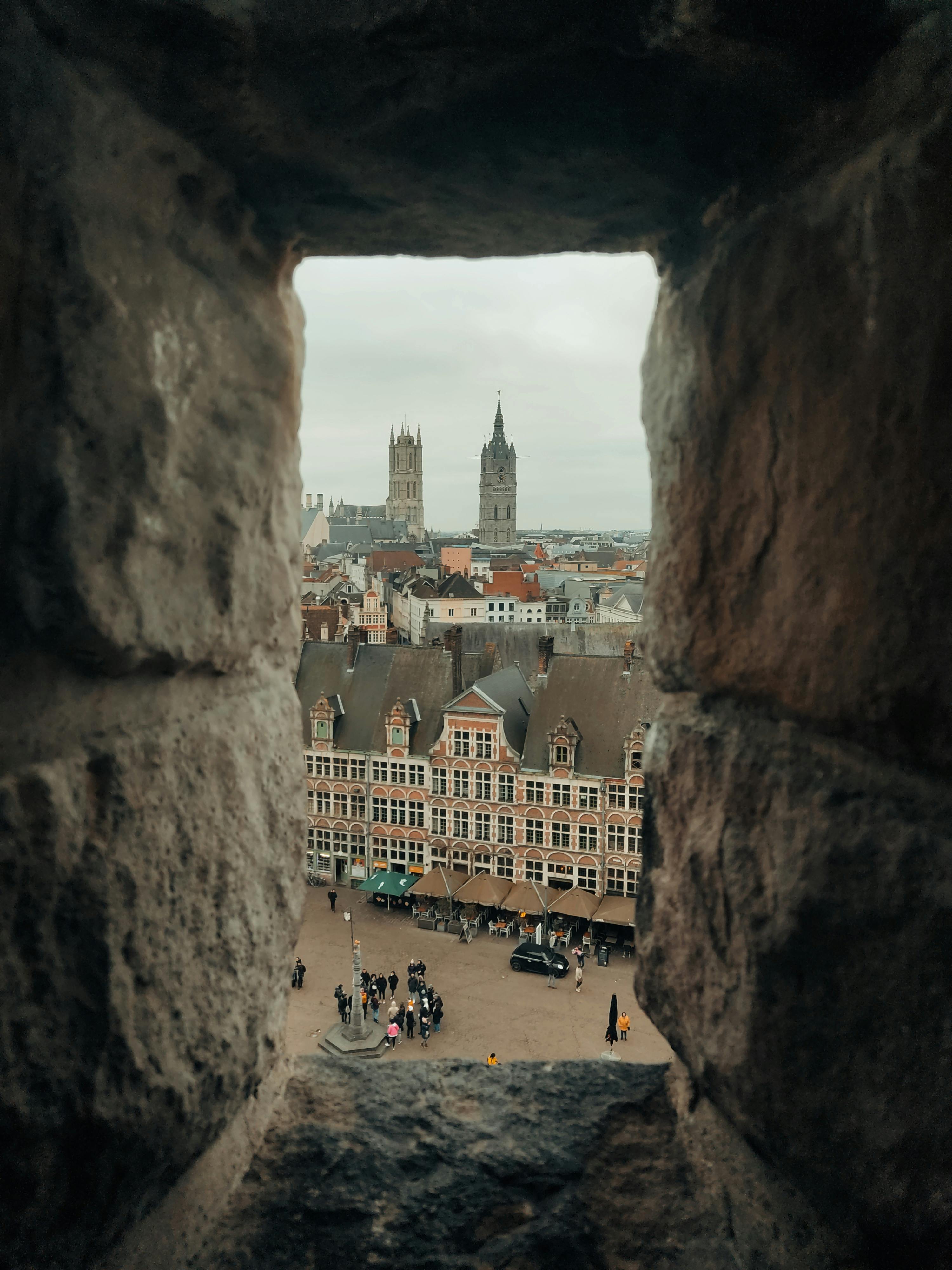 Unique view of Ghent cityscape framed by ancient castle stones, perfect for travel enthusiasts.