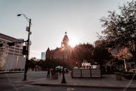 城市十字路口的日出景观中，红色历史建筑、人物与城市环境交相辉映