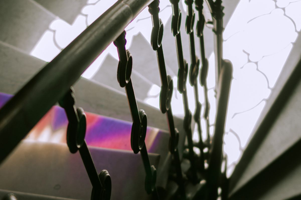 Scară în spirală cu balustradă din fier forjat cu ornamente, sub o lumină difuză