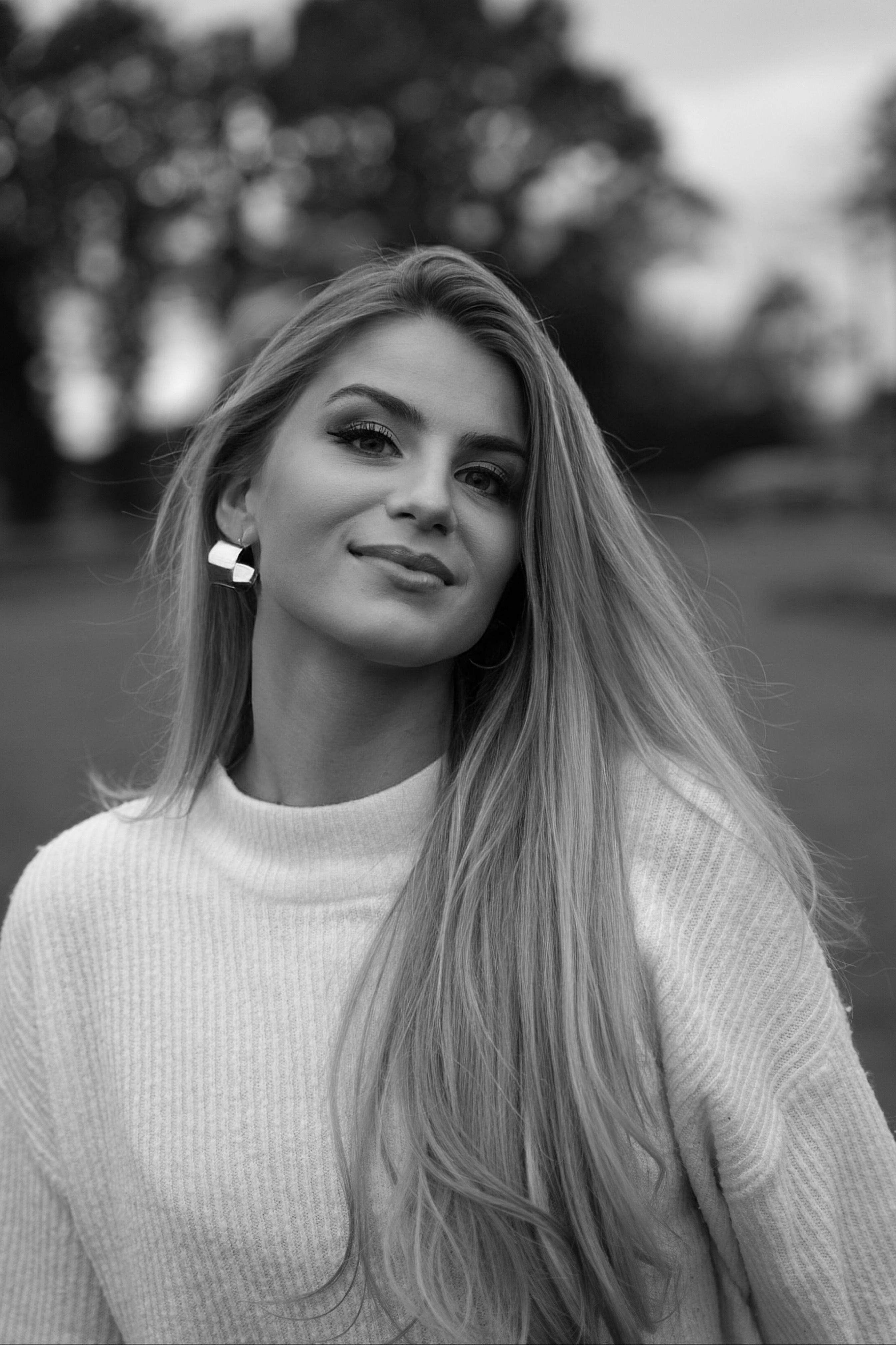 A stunning black and white portrait of a woman with long hair in a Hamburg park, radiating elegance.
