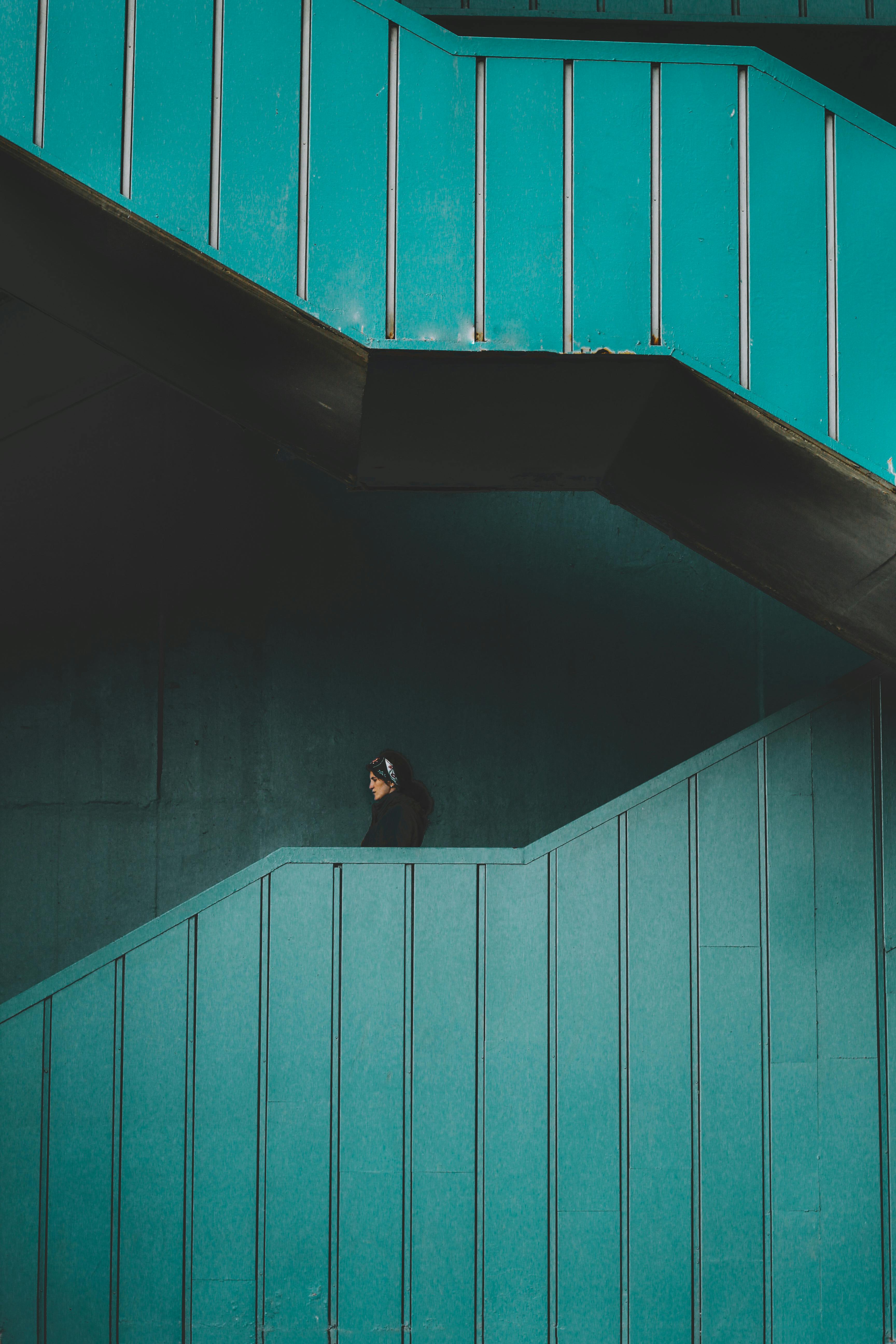 A woman walks on a stylish teal staircase, showcasing modern urban design.