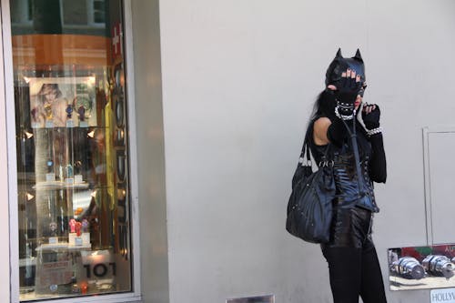 Женщина, опираясь на стену в костюме черной кошки