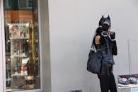 一张街头风格照片中，一位穿着猫女服装的女人在时装店外摆姿势