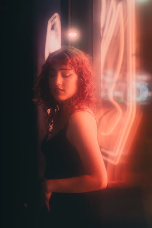 Young Woman Posing next to Red Neon Lights