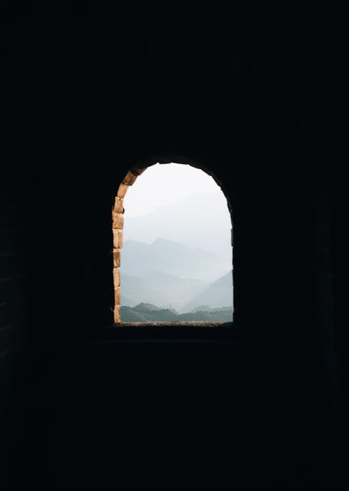 Arched Window in the Castle of Grate Wall Overlooking the Mountains