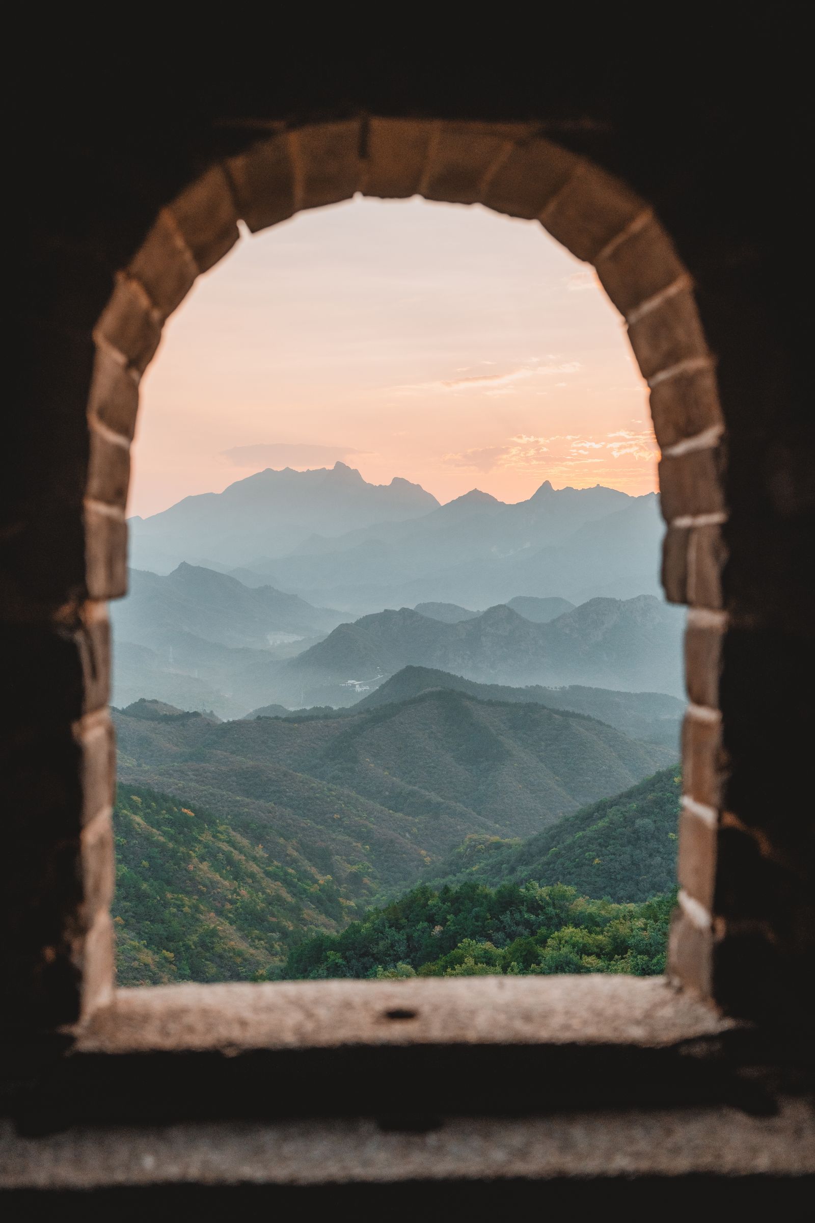 As montanhas e a Grande Muralha vistas por uma janela de pedra ao amanhecer