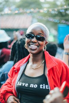 Happy woman with short hair and sunglasses enjoying an outdoor event.