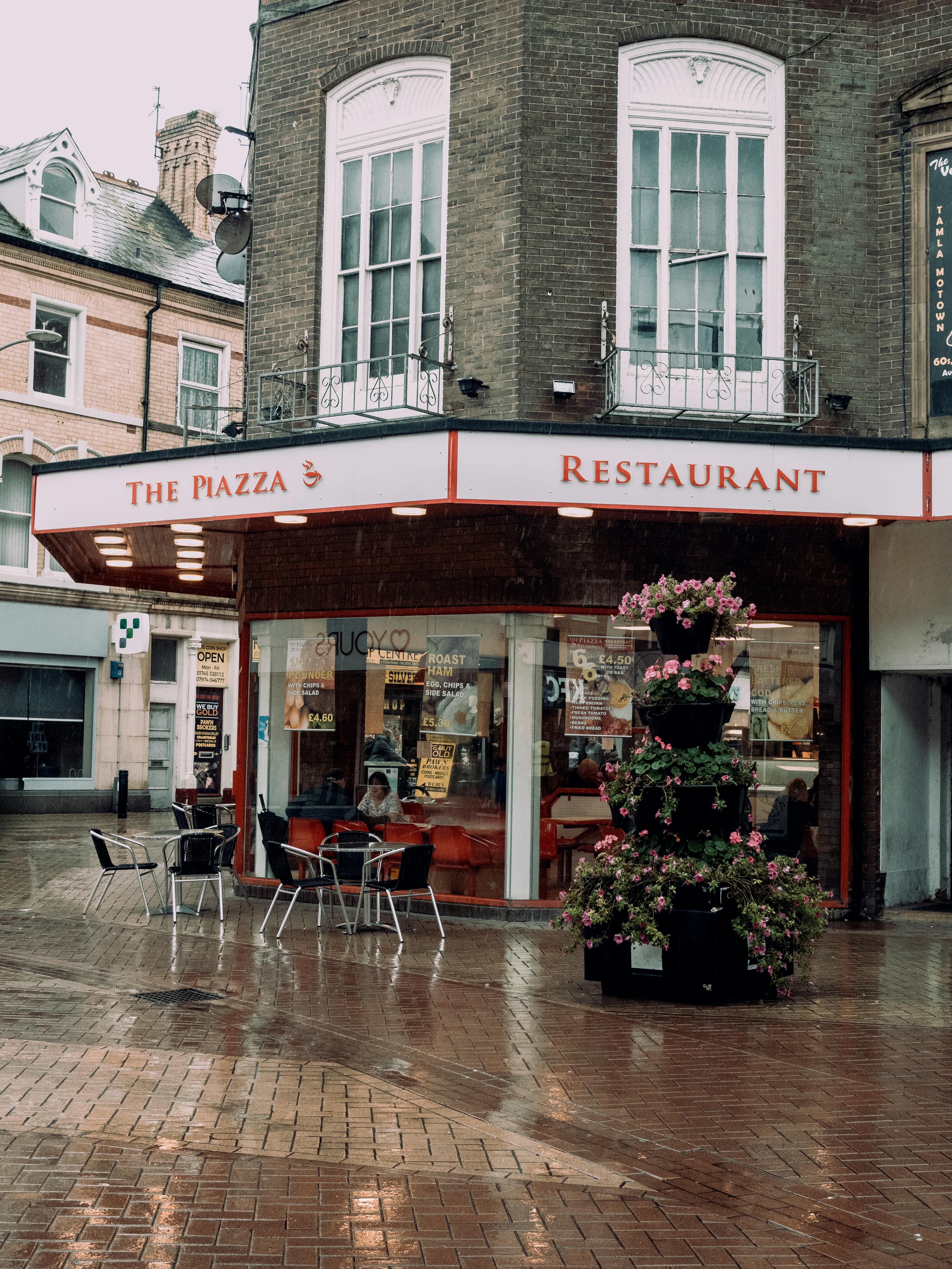A quaint restaurant on a rainy city street, showcasing cozy outdoor cafe vibes.