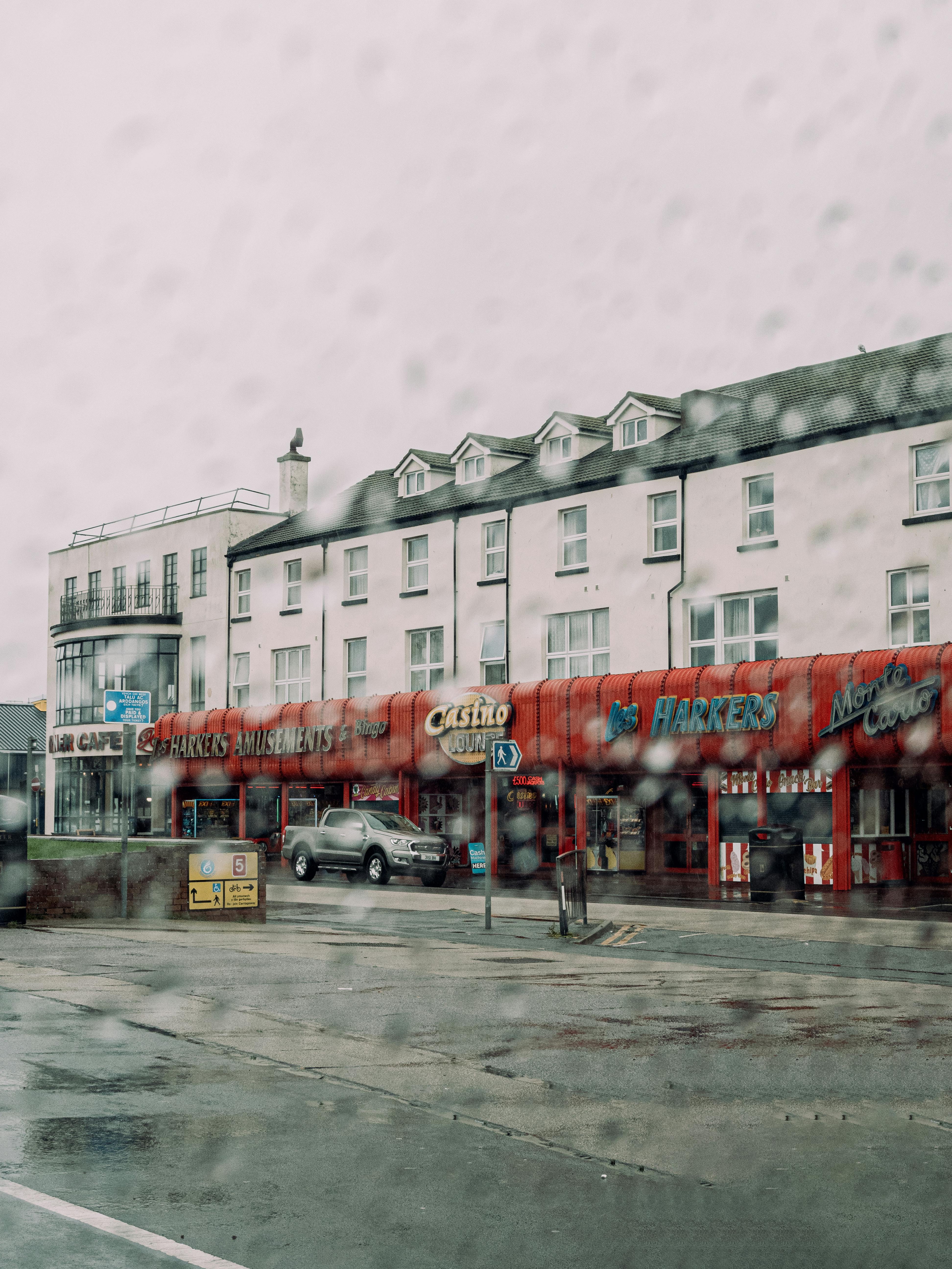 A rainy day scene of an amusement arcade in downtown Rhyl, Wales, highlighting urban life.